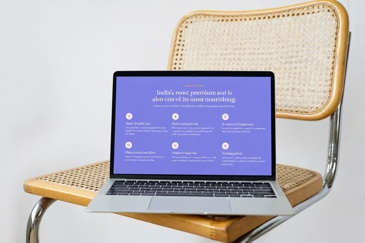 A laptop on a cane-seated chrome chair showing the lavender benefits section of the store: India's most premium nut is also one of its most nourishing, with six short benefits