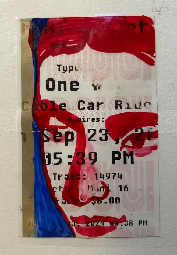 A face painted in red, white and blue over a cable car ticket stub.